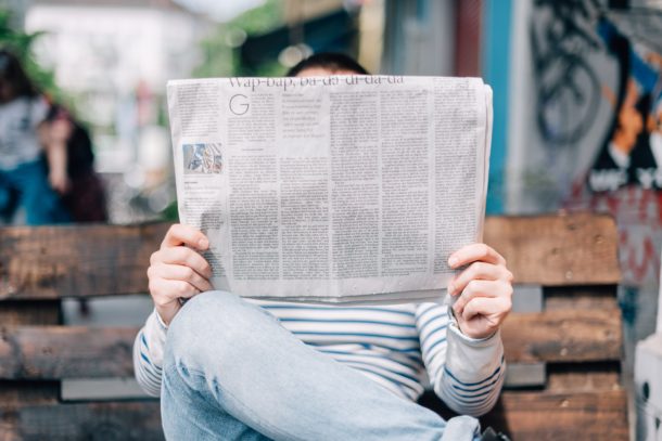 man sitting on bench reading newspaper